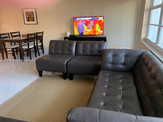 A living room features a dark gray sectional sofa, a dining set, and a television — 100 Lincoln Rd # 819, Miami Beach FL 33139, MIAMI BEACH, FL