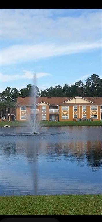 A multi-story apartment building sits behind a pond with a central water fountain — 4600 E MOODY BOULEVARD UNIT 8B, BUNNELL, FL