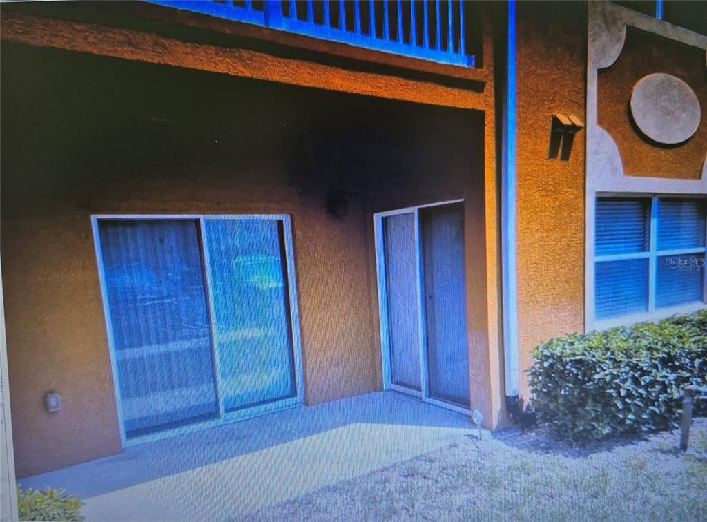 A ground-level patio with two sliding glass doors sits beneath an upper-level balcony — 4600 E MOODY BOULEVARD UNIT 8B, BUNNELL, FL