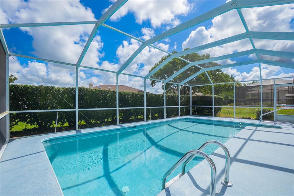 A rectangular swimming pool is enclosed by a white screen cage in a backyard — 3943 W FIELDWOOD COURT, LECANTO, FL