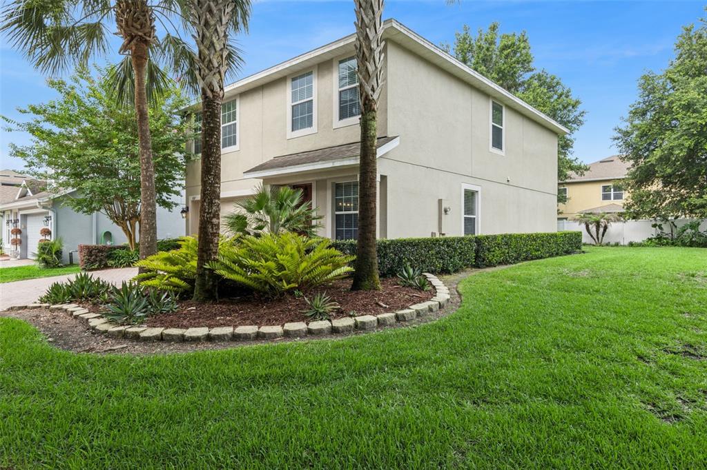 A two-story house with a beige stucco exterior, palm trees, and a landscaped front yard — 657 PREAKNESS CIRCLE, DELAND, FL