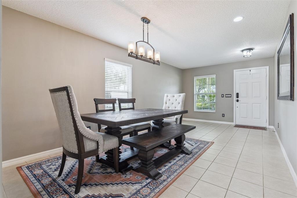 A dining room features a wooden table with a bench and chairs on a patterned rug — 657 PREAKNESS CIRCLE, DELAND, FL