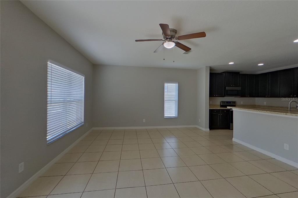 An open-concept living area with tile flooring, a ceiling fan, and an adjacent kitchen — 2800 GLENDIVE DRIVE, KISSIMMEE, FL