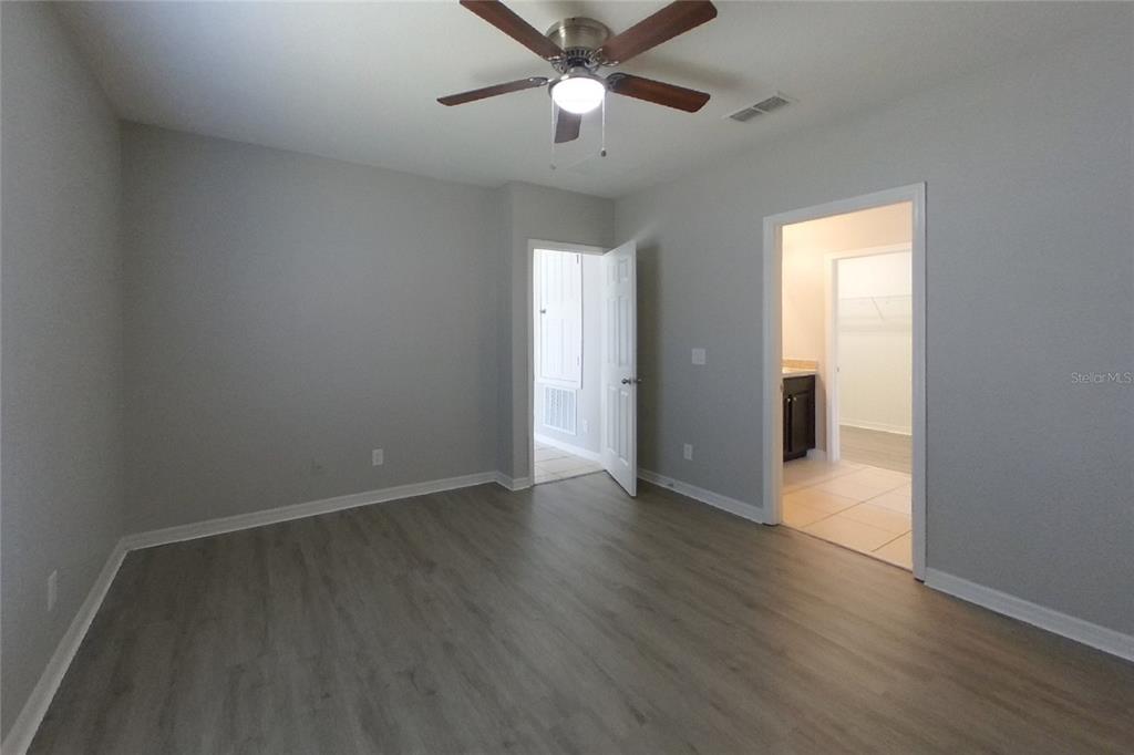 A bedroom with gray walls, wood-look flooring, a ceiling fan, and two doorways — 2800 GLENDIVE DRIVE, KISSIMMEE, FL