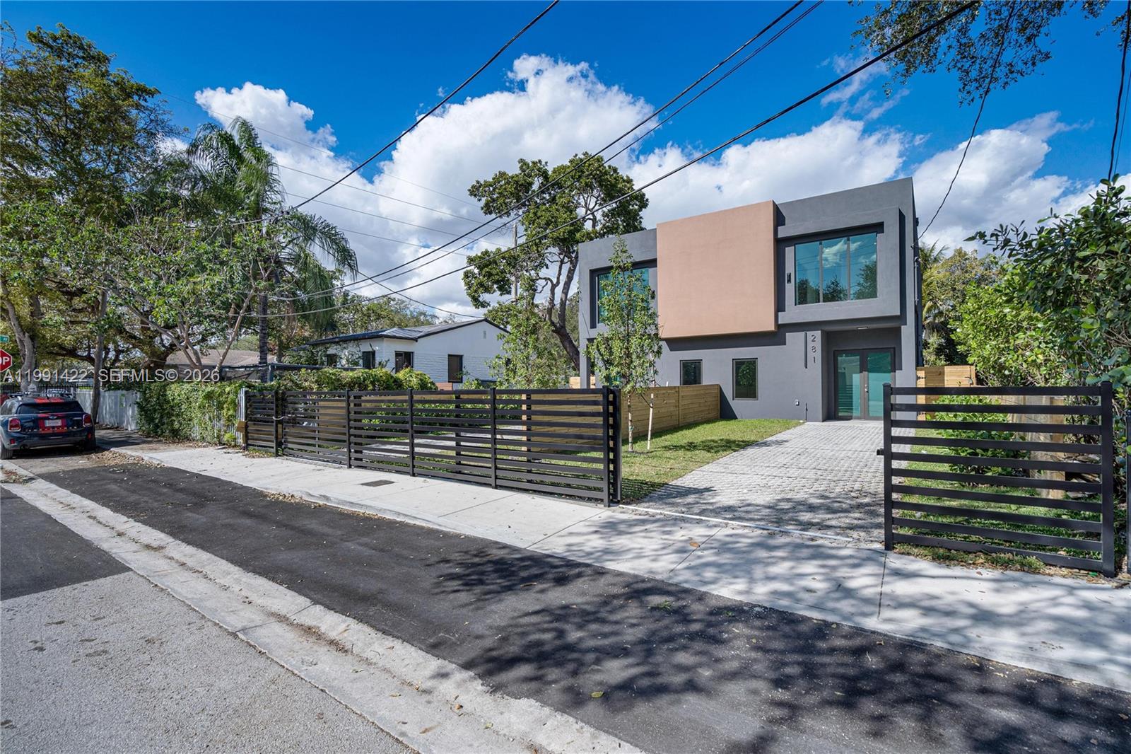 A modern two-story house with a gray and tan exterior stands behind a black fence — 283 NW 52 St # 283, Miami FL 33127, MIAMI, FL