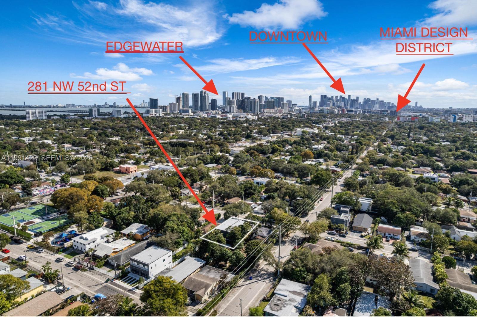 An aerial view shows a residential property surrounded by trees with city skylines in the distance — 283 NW 52 St # 283, Miami FL 33127, MIAMI, FL