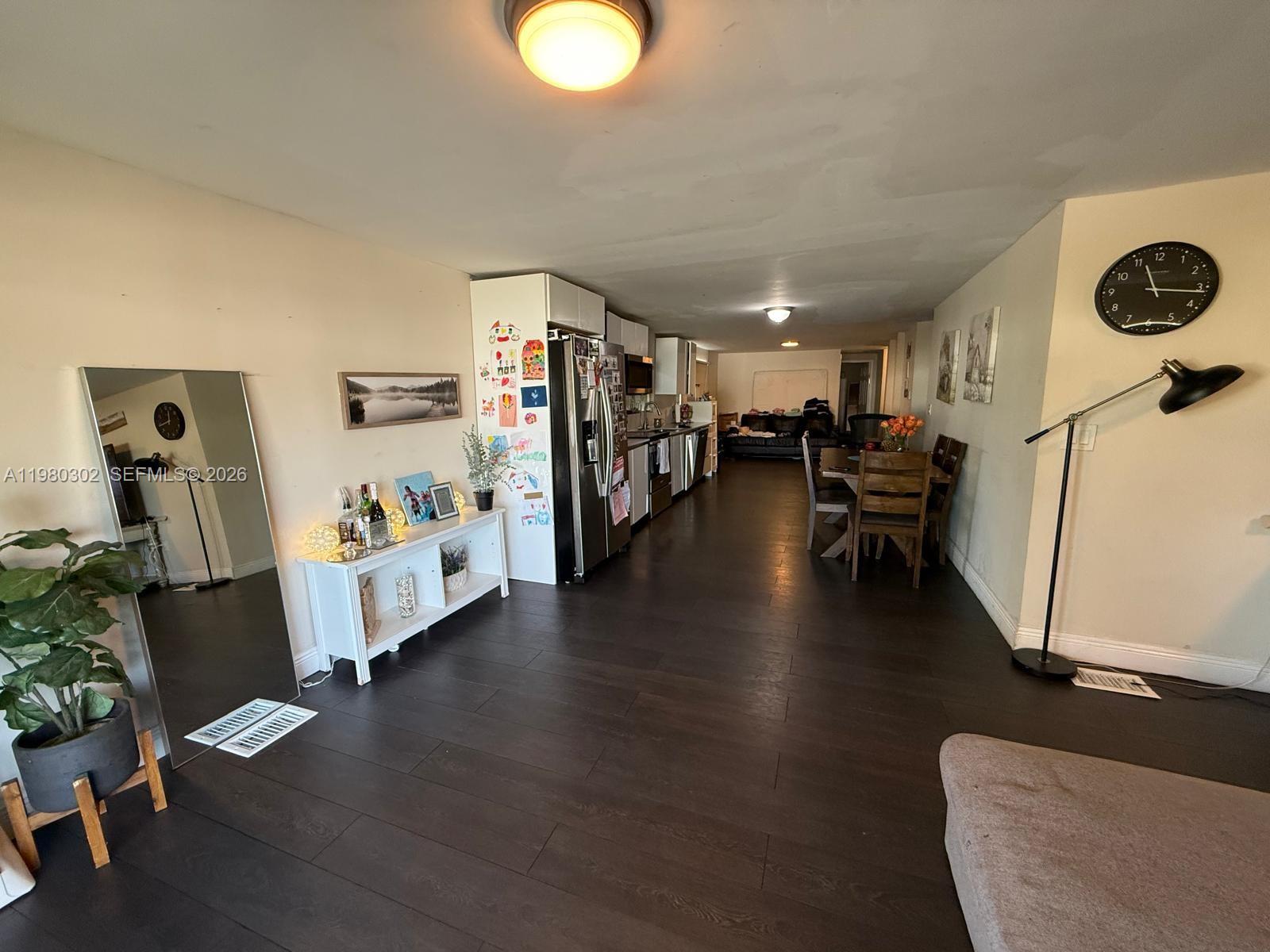 An open-concept living and dining area features dark wood flooring and a galley kitchen — 5290 SW 22nd Ter, Dania Beach FL 33312, DANIA BEACH, FL