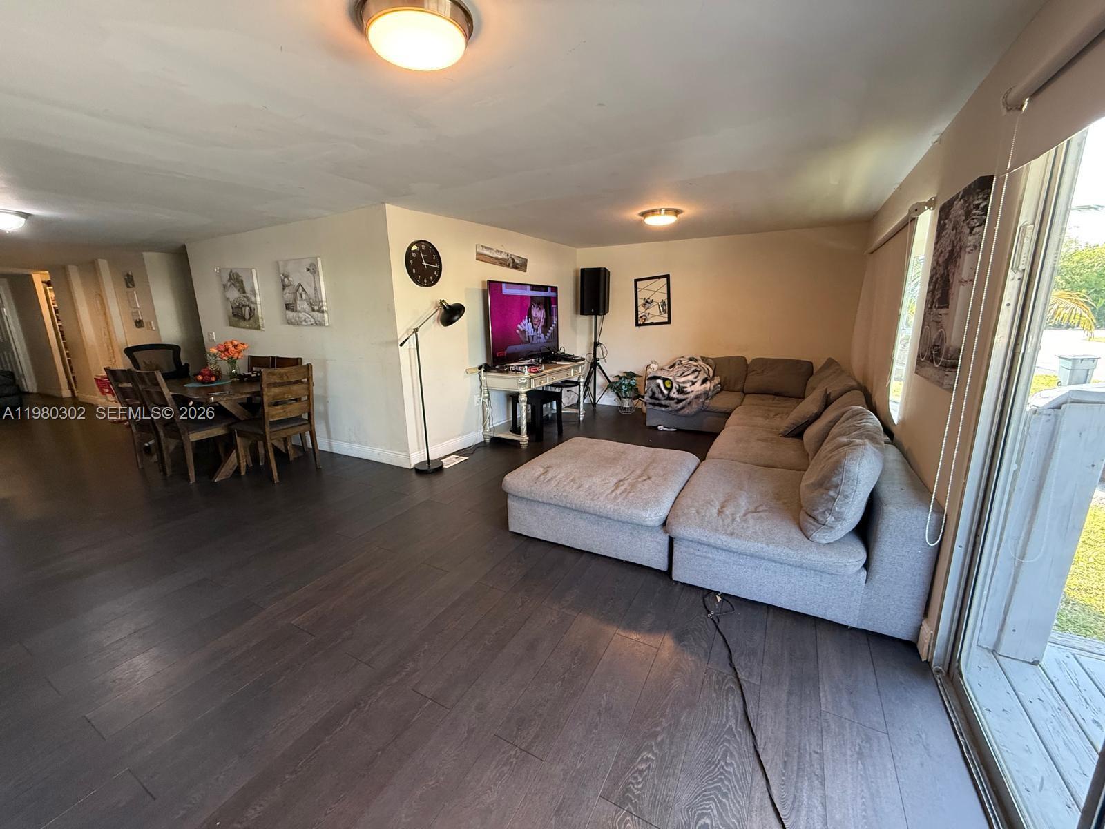 A living room with dark wood floors, a gray sectional sofa, and an adjacent dining area — 5290 SW 22nd Ter, Dania Beach FL 33312, DANIA BEACH, FL