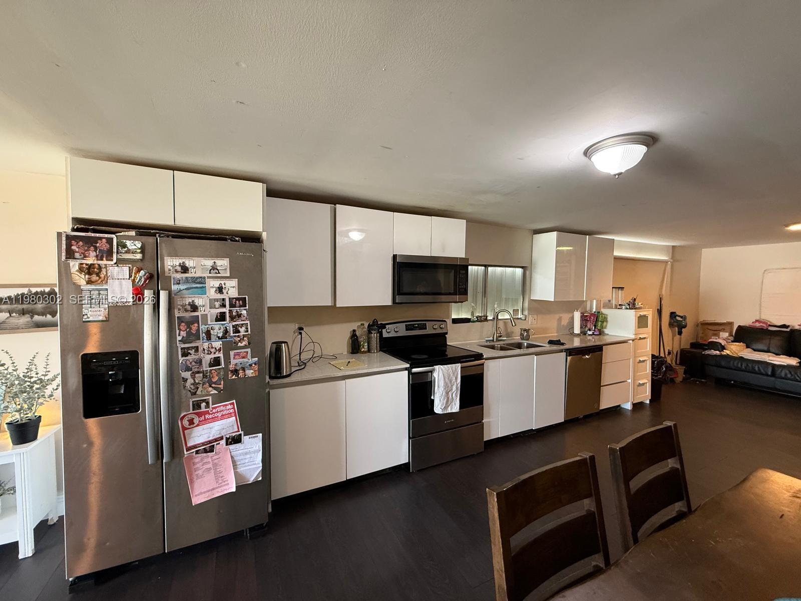 A kitchen features white cabinets, stainless steel appliances, and dark wood-look flooring — 5290 SW 22nd Ter, Dania Beach FL 33312, DANIA BEACH, FL