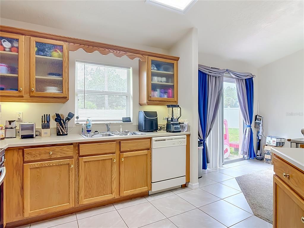 A kitchen features oak cabinets, white appliances, a double sink, and a sliding glass door — 8 BAINBRIDGE LANE, PALM COAST, FL