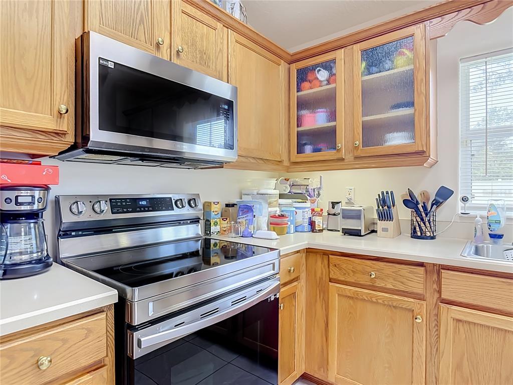 A kitchen features oak cabinets, stainless steel appliances, and a light-colored countertop — 8 BAINBRIDGE LANE, PALM COAST, FL