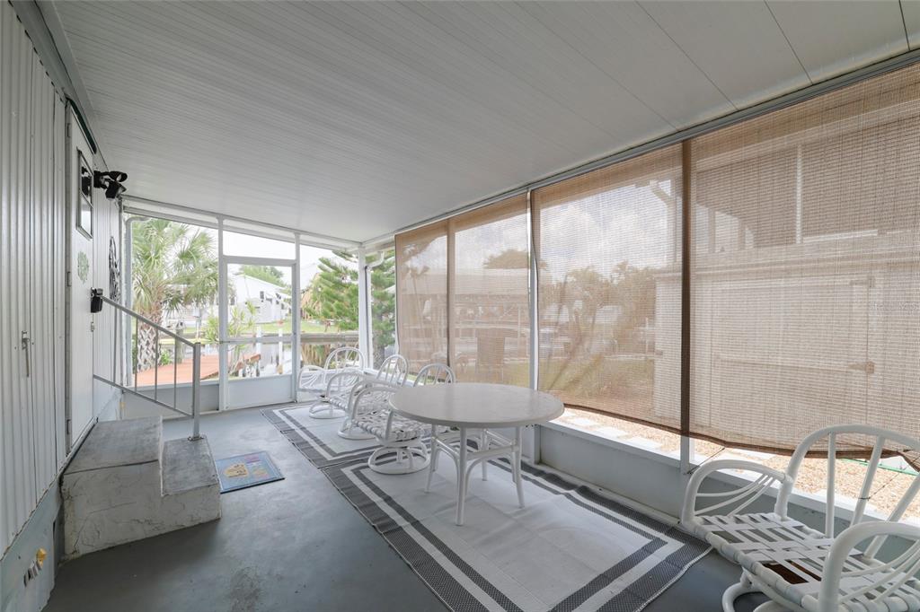 A screened-in porch features a white table, matching chairs, and a view of a canal — 3119 SUNNY HARBOR DRIVE, PUNTA GORDA, FL