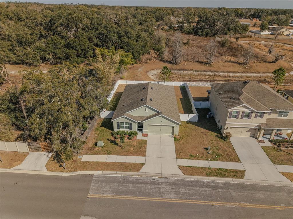 An aerial view shows a single-story house with a two-car garage and a fenced backyard — 5618 GEIGER ESTATES DRIVE, ZEPHYRHILLS, FL