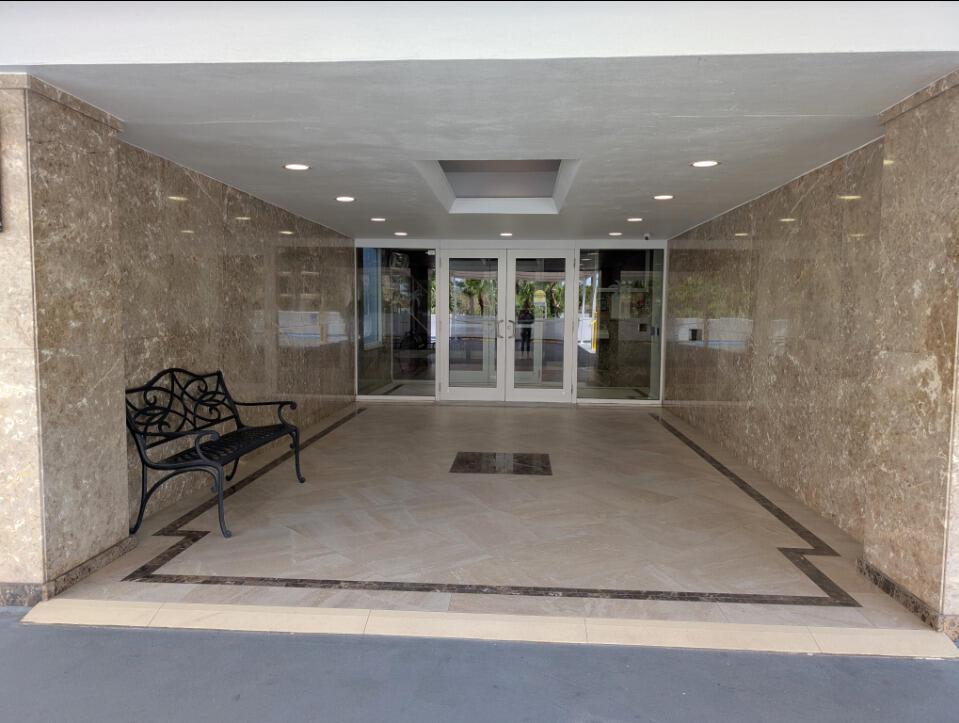 A covered building entrance features marble walls, a tiled floor with a border, and a bench — 1370 S Ocean Boulevard S # 1403, Pompano Beach FL 33062, POMPANO BEACH, FL