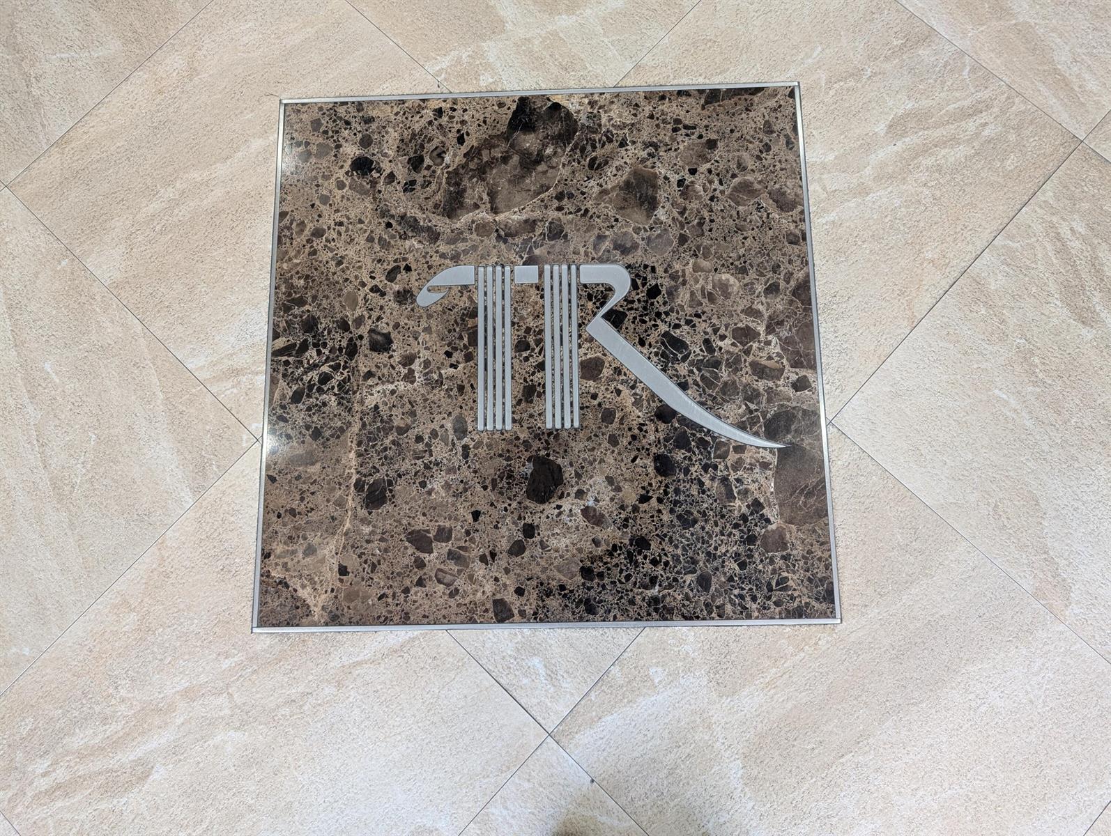 A square brown marble floor inlay features a silver metal logo centered on the tile — 1370 S Ocean Boulevard S # 1403, Pompano Beach FL 33062, POMPANO BEACH, FL