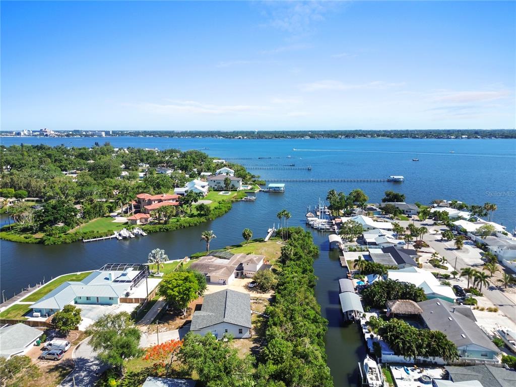An aerial view shows waterfront homes along a canal leading into a large bay — 901 24TH AVENUE W, PALMETTO, FL