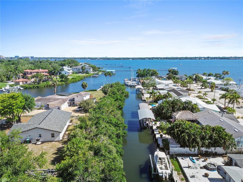 An aerial view shows a canal leading to a bay, surrounded by houses and vegetation — 901 24TH AVENUE W, PALMETTO, FL