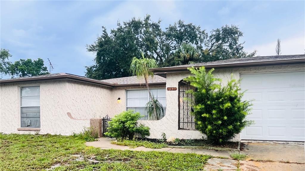 A single-story house with a white stucco exterior, a garage, and a front yard — 7310 BRENTWOOD DRIVE, PORT RICHEY, FL