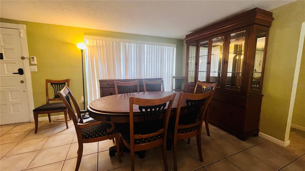 A dining room features a wooden table with chairs, a large hutch, and tile flooring — 7310 BRENTWOOD DRIVE, PORT RICHEY, FL