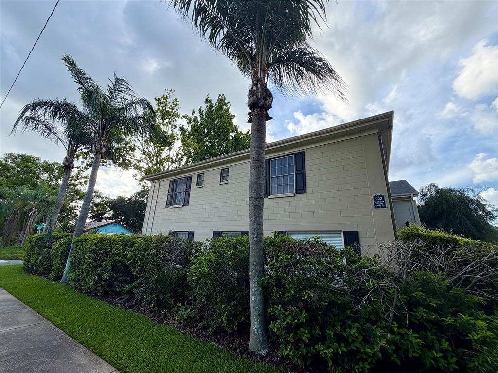 A two-story building with tan block walls, dark shutters, and palm trees in the foreground — 223 WINDSOR STREET UNIT 6, LAKELAND, FL