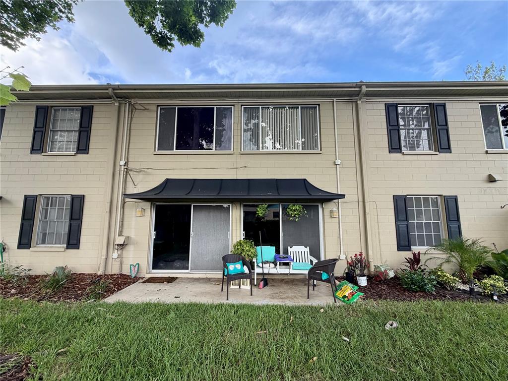 The exterior of a two-story townhouse features a concrete patio and sliding glass doors — 223 WINDSOR STREET UNIT 6, LAKELAND, FL