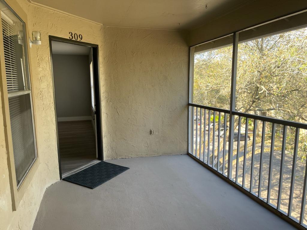 A covered balcony with a screened enclosure, concrete flooring, and an entrance to unit 309 — 623 DORY LANE UNIT 309, ALTAMONTE SPRINGS, FL
