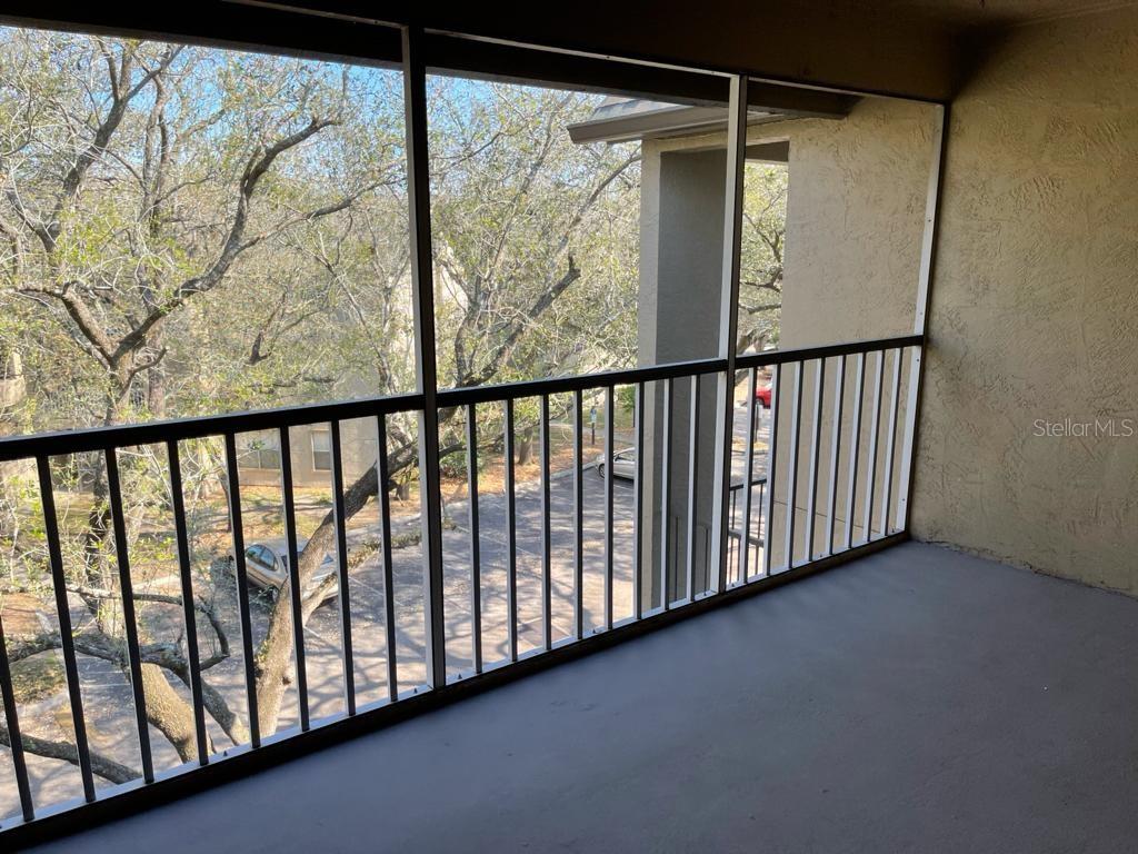 A screened-in balcony with a metal railing overlooks a parking lot and trees — 623 DORY LANE UNIT 309, ALTAMONTE SPRINGS, FL