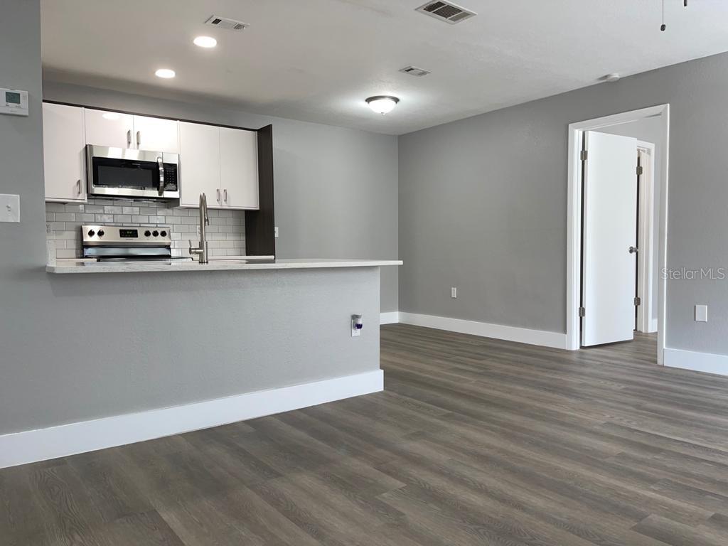 A kitchen with white cabinets and a breakfast bar opens into a gray-walled living area — 623 DORY LANE UNIT 309, ALTAMONTE SPRINGS, FL