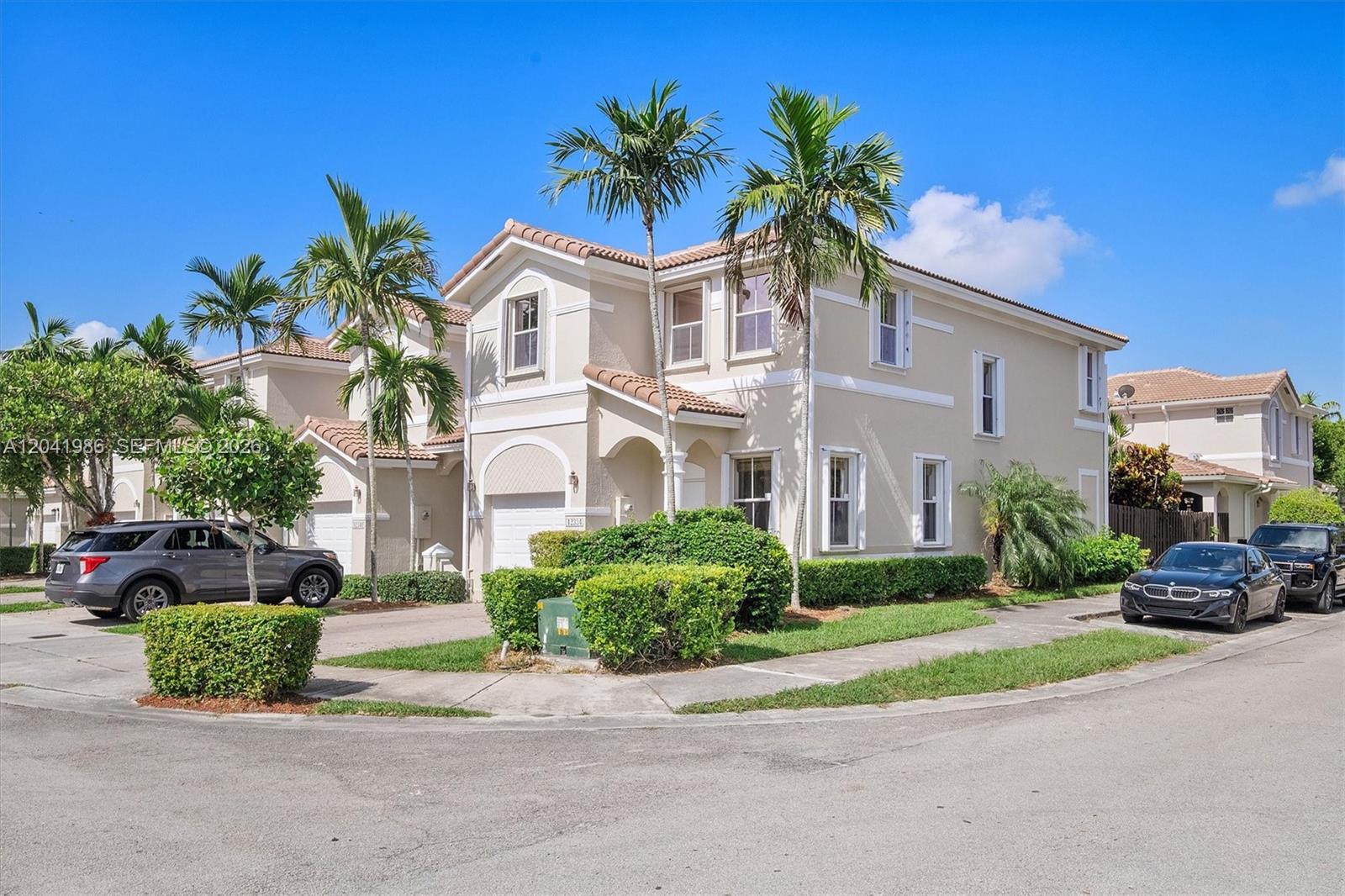 A two-story beige residential building with a tiled roof, palm trees, and parked cars — 12334 SW 124th Path, Miami FL 33186, MIAMI, FL