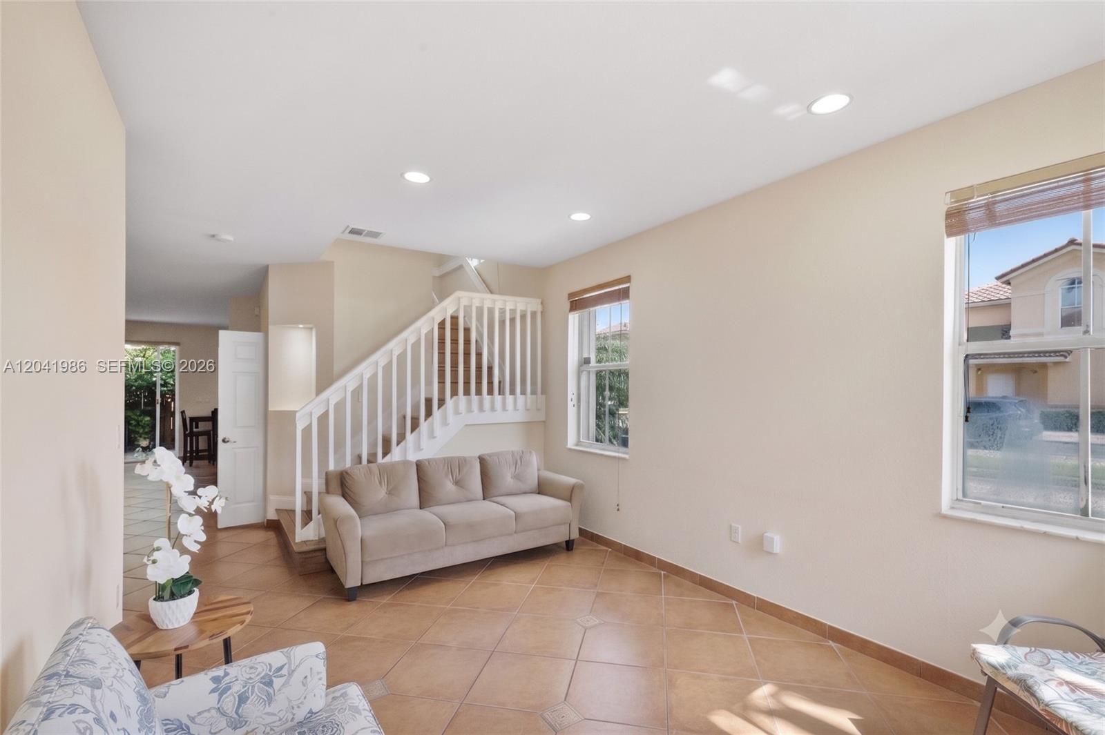A living room features a beige sofa, a staircase with white railings, and tile flooring — 12334 SW 124th Path, Miami FL 33186, MIAMI, FL