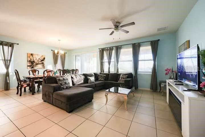 A living room and dining area with tile floors, a sectional sofa, and large windows — 6078 BROAD OAK DRIVE, DAVENPORT, FL