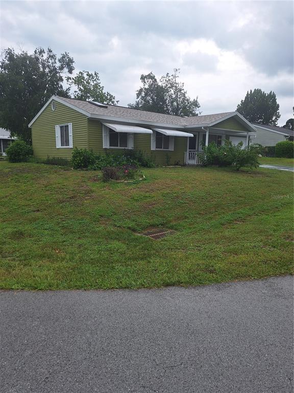 A single-story house with green siding and white window awnings sits on a grassy lot — 8942 SW 109TH LANE, OCALA, FL