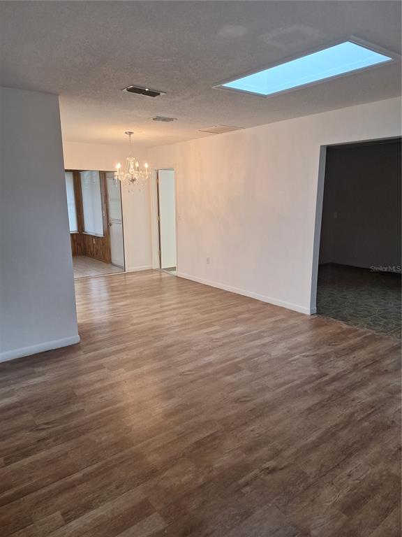 An interior view of a room with wood-look flooring, a chandelier, and a large skylight — 8942 SW 109TH LANE, OCALA, FL