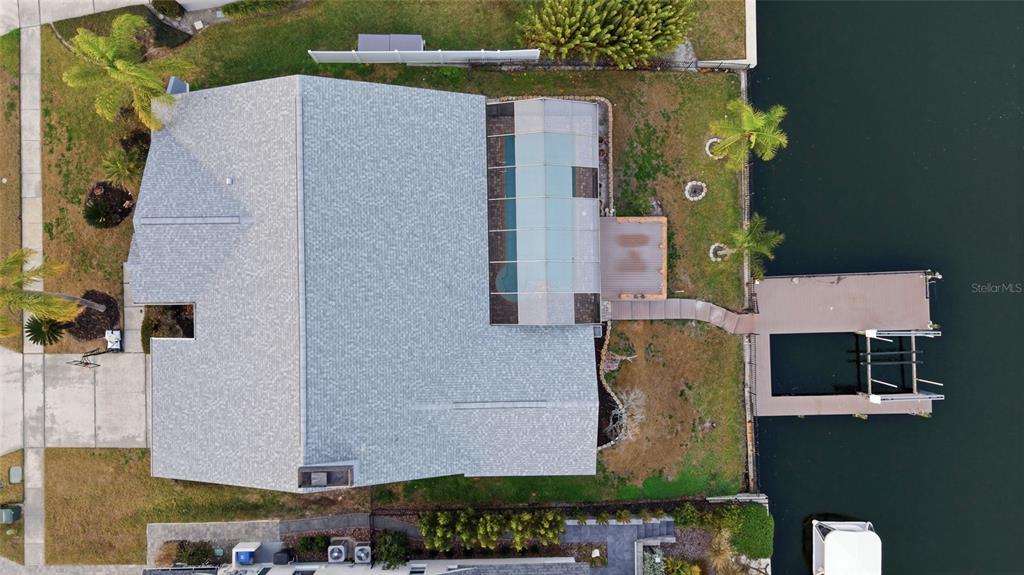 An aerial view shows a house with a screened pool, a wooden dock, and landscaping — 4157 SALTWATER BOULEVARD, TAMPA, FL