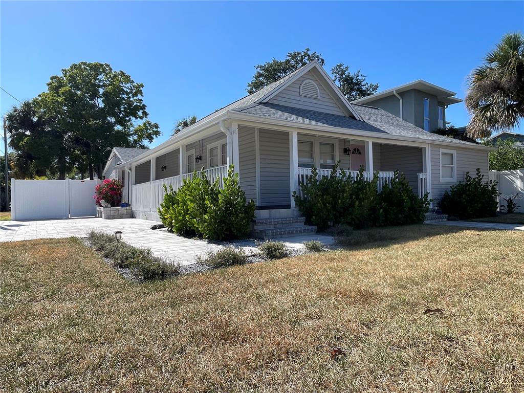 A gray-sided house with a front porch, paved patio, and white vinyl fencing — 7315 S MASCOTTE STREET, TAMPA, FL