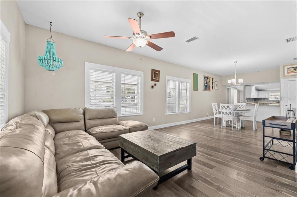A living room with a beige sectional sofa, wood coffee table, and light wood flooring — 7315 S MASCOTTE STREET, TAMPA, FL