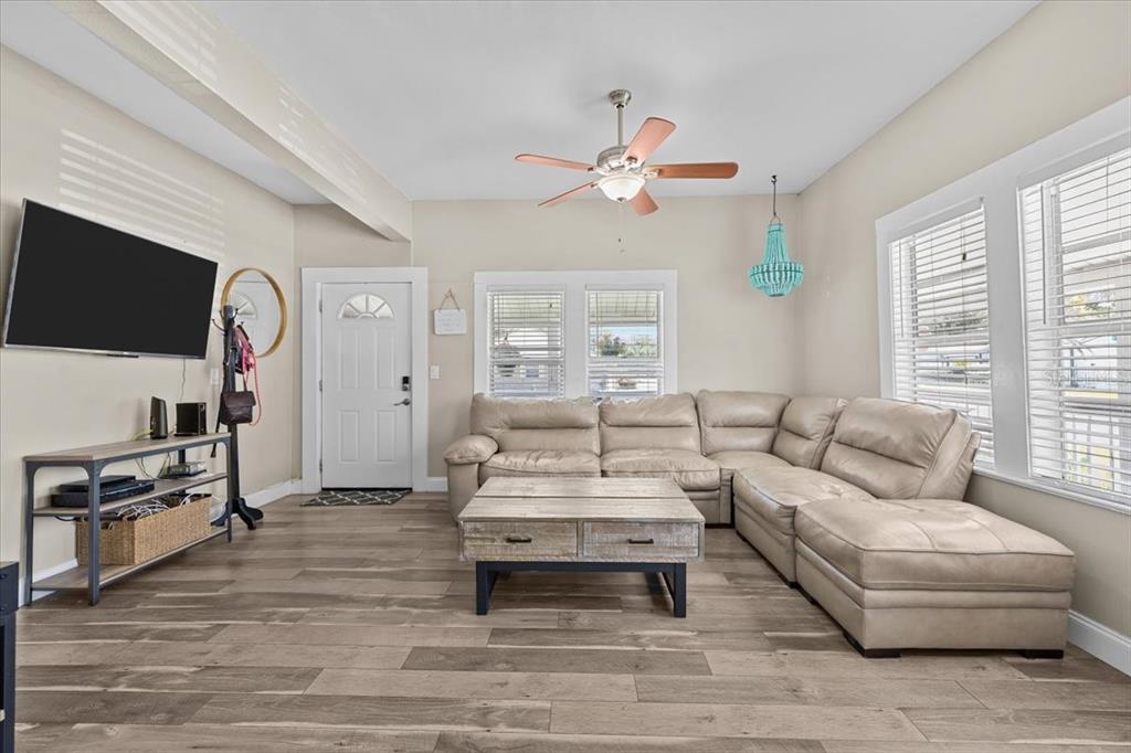 A living room features a beige sectional sofa, a wooden coffee table, and wood-look flooring — 7315 S MASCOTTE STREET, TAMPA, FL