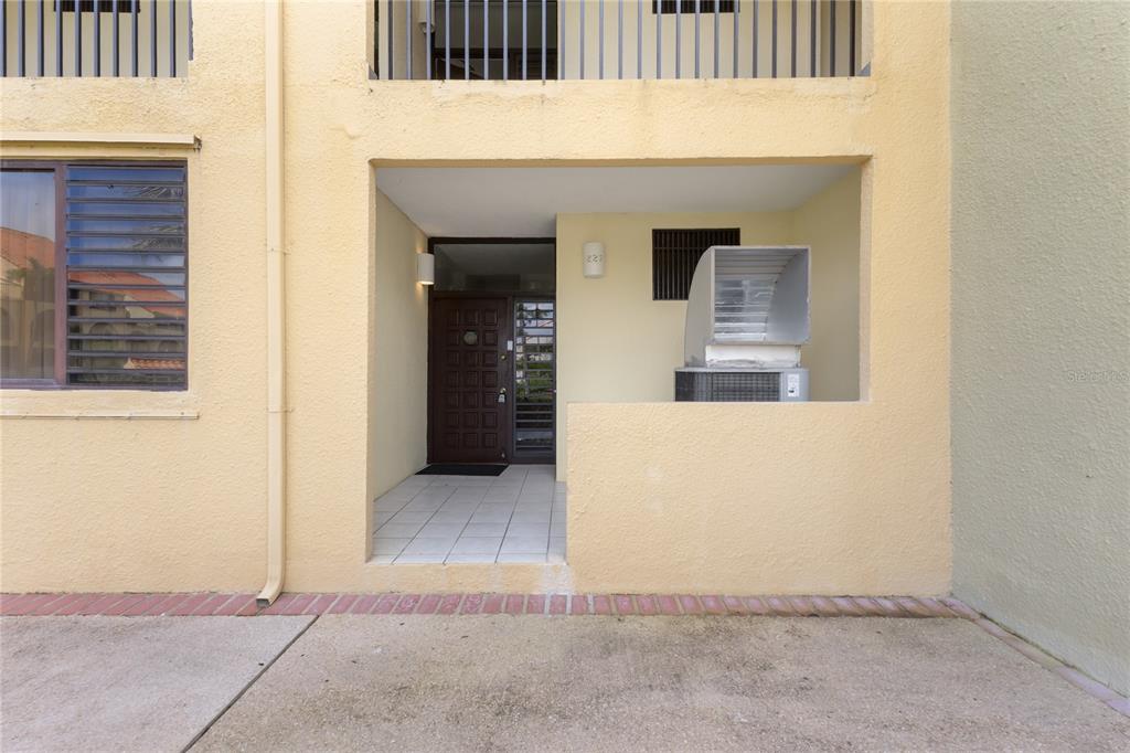 The exterior of a yellow stucco building features a recessed entryway with a tiled floor — 227 BEACH VILLAGE UNIT 227, HUMACAO, PR