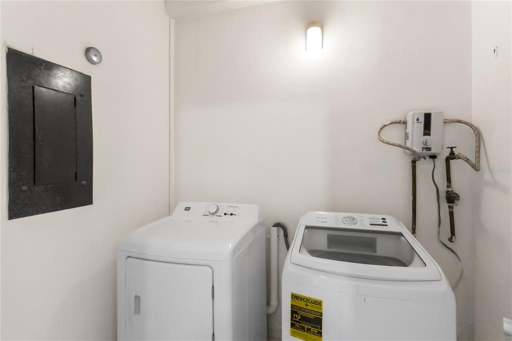 A laundry room features a white washer and dryer next to an electrical panel — 227 BEACH VILLAGE UNIT 227, HUMACAO, PR