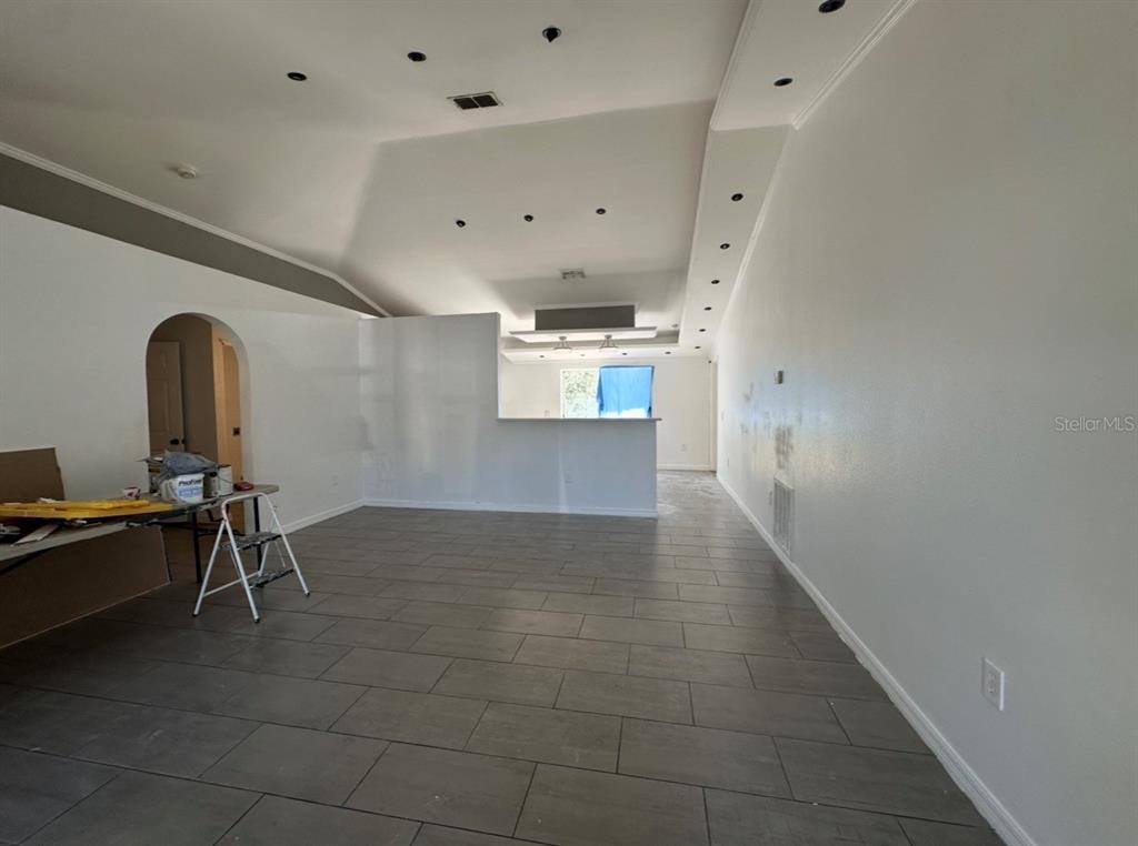 An open-concept living area features vaulted ceilings, recessed lighting, and gray tile flooring — 1316 BURNLEY COURT, KISSIMMEE, FL