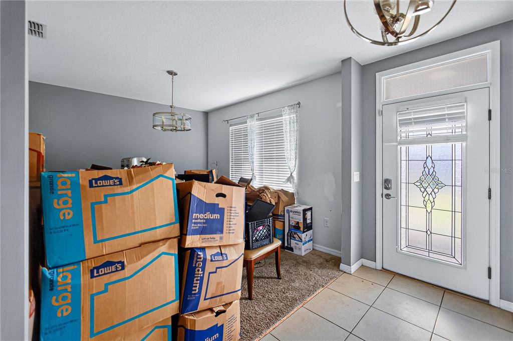 A room with tile flooring, gray walls, a front door, and several cardboard moving boxes — 6022 GREY HERON DRIVE, WINTER HAVEN, FL