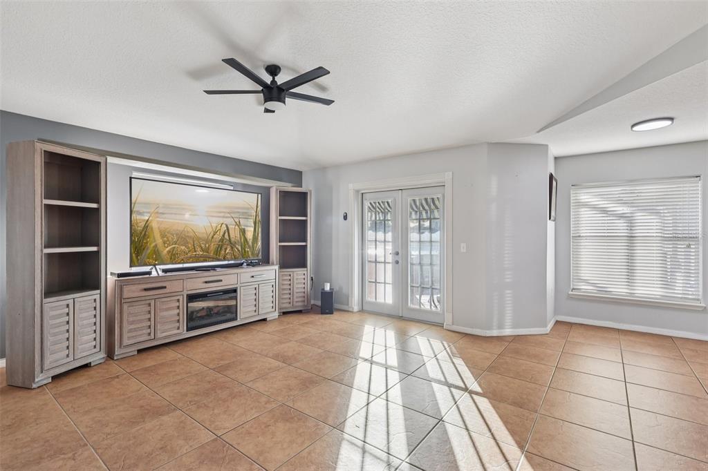 A living room features tile flooring, a media console with a fireplace, and glass doors — 402 OHIO WAY, KISSIMMEE, FL