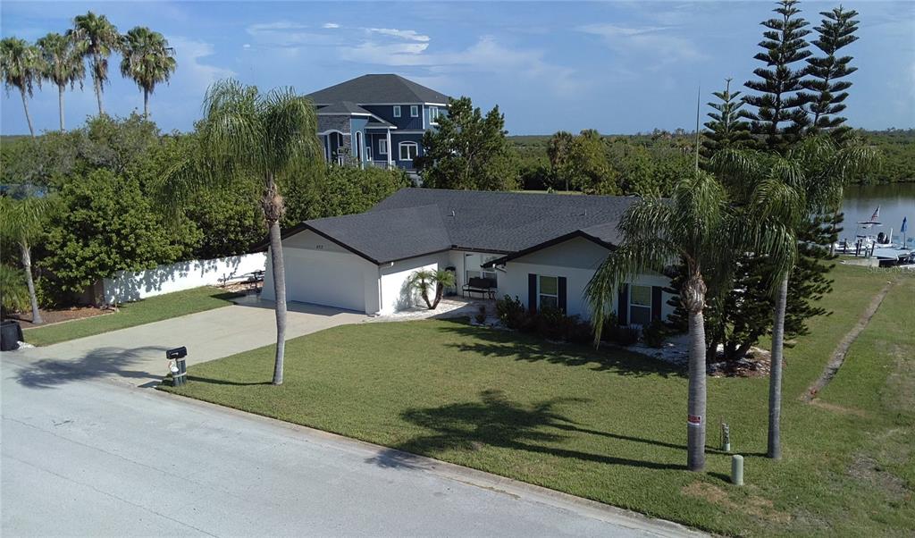 An aerial view of a single-story house with a white exterior, dark roof, and palm trees — 5717 SEABREEZE DRIVE, PORT RICHEY, FL