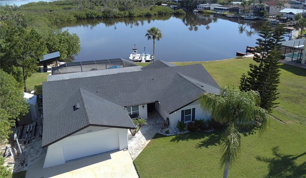 An aerial view of a single-story house with a garage, pool cage, and private dock — 5717 SEABREEZE DRIVE, PORT RICHEY, FL