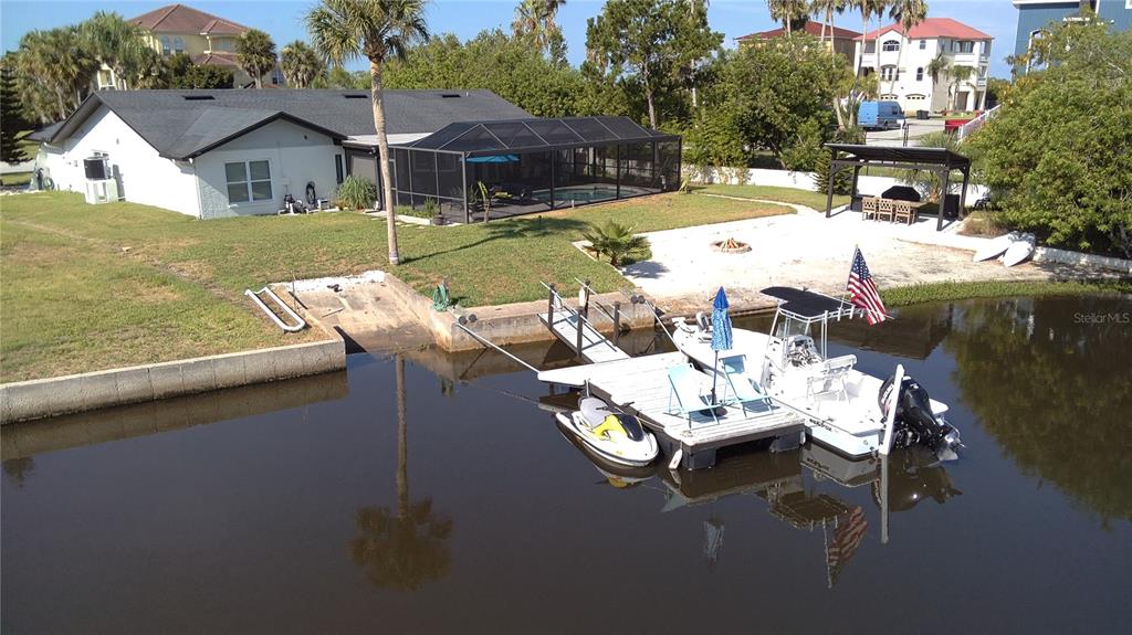 An aerial view shows a house with a screened pool, boat dock, and jet ski — 5717 SEABREEZE DRIVE, PORT RICHEY, FL
