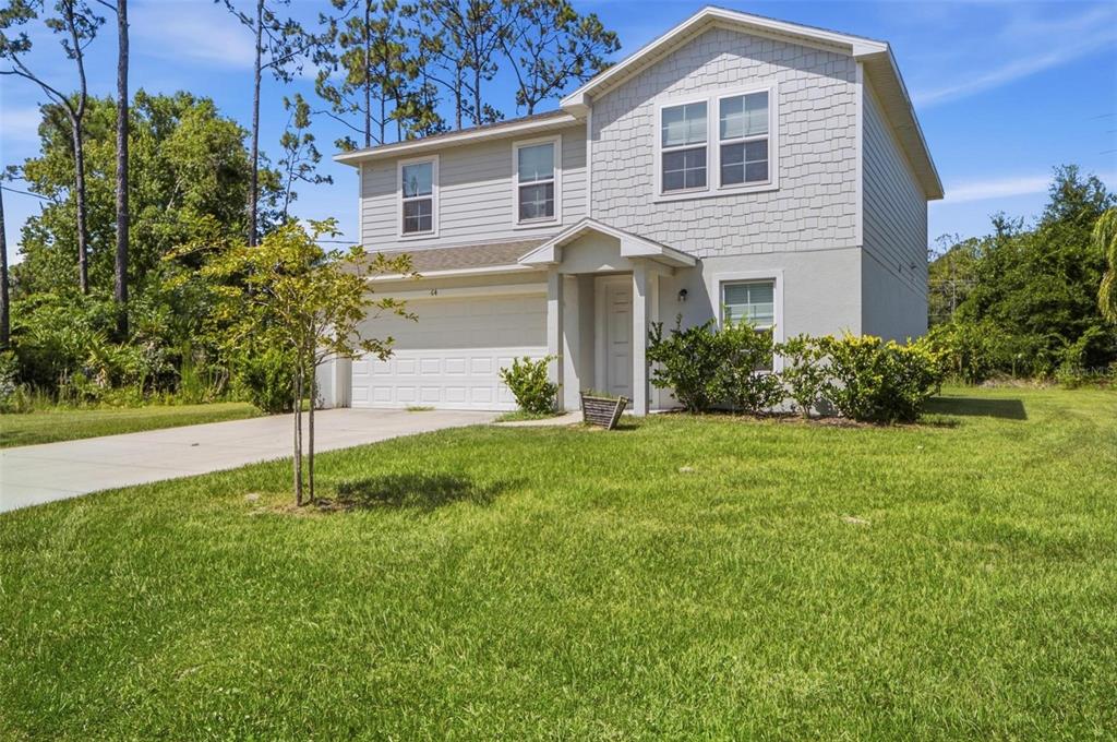 A two-story light gray house with a two-car garage and a front lawn — 64 FOXHALL LANE, PALM COAST, FL