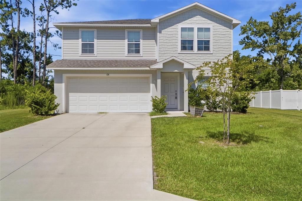 A two-story suburban house with light gray siding, a concrete driveway, and a white fence — 64 FOXHALL LANE, PALM COAST, FL