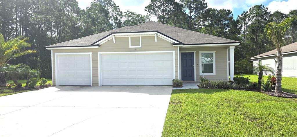 A single-story house with a tan exterior, a three-car garage, and a dark blue front door — 16 PINNACLE PLACE, BUNNELL, FL