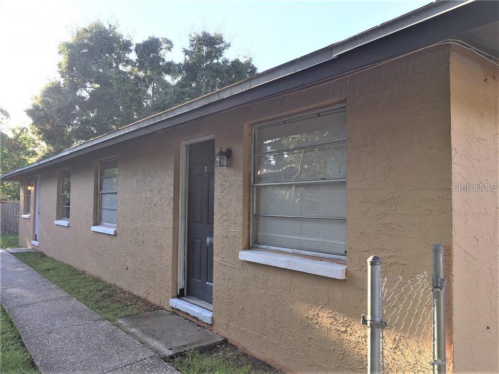 A tan exterior wall of a building features a dark door and several windows — 8306 N 17TH STREET, TAMPA, FL