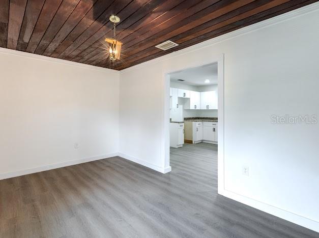 A room with wood-plank ceiling and light-colored flooring leads into a white kitchen — 1440 SE 1ST TERRACE, GAINESVILLE, FL